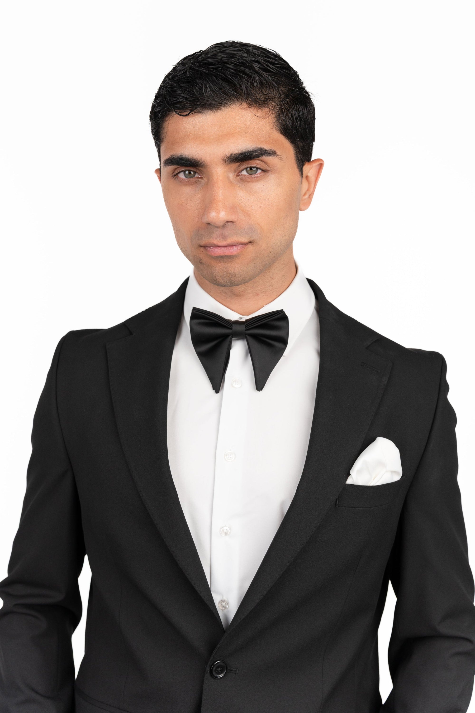 Man wearing a black tuxedo with a bow tie on a white background