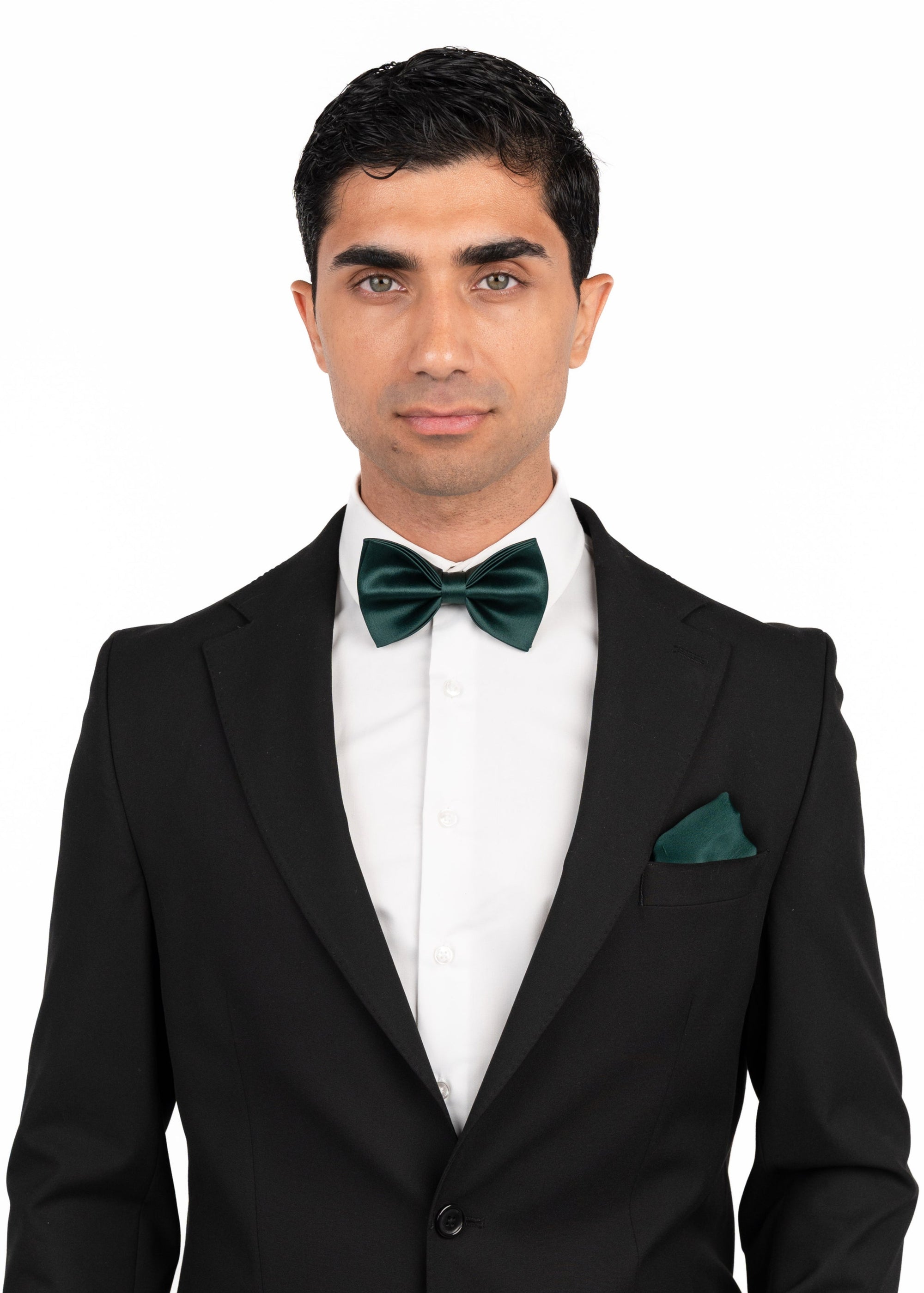 Man wearing a black suit with green bow tie and pocket square on a white background
