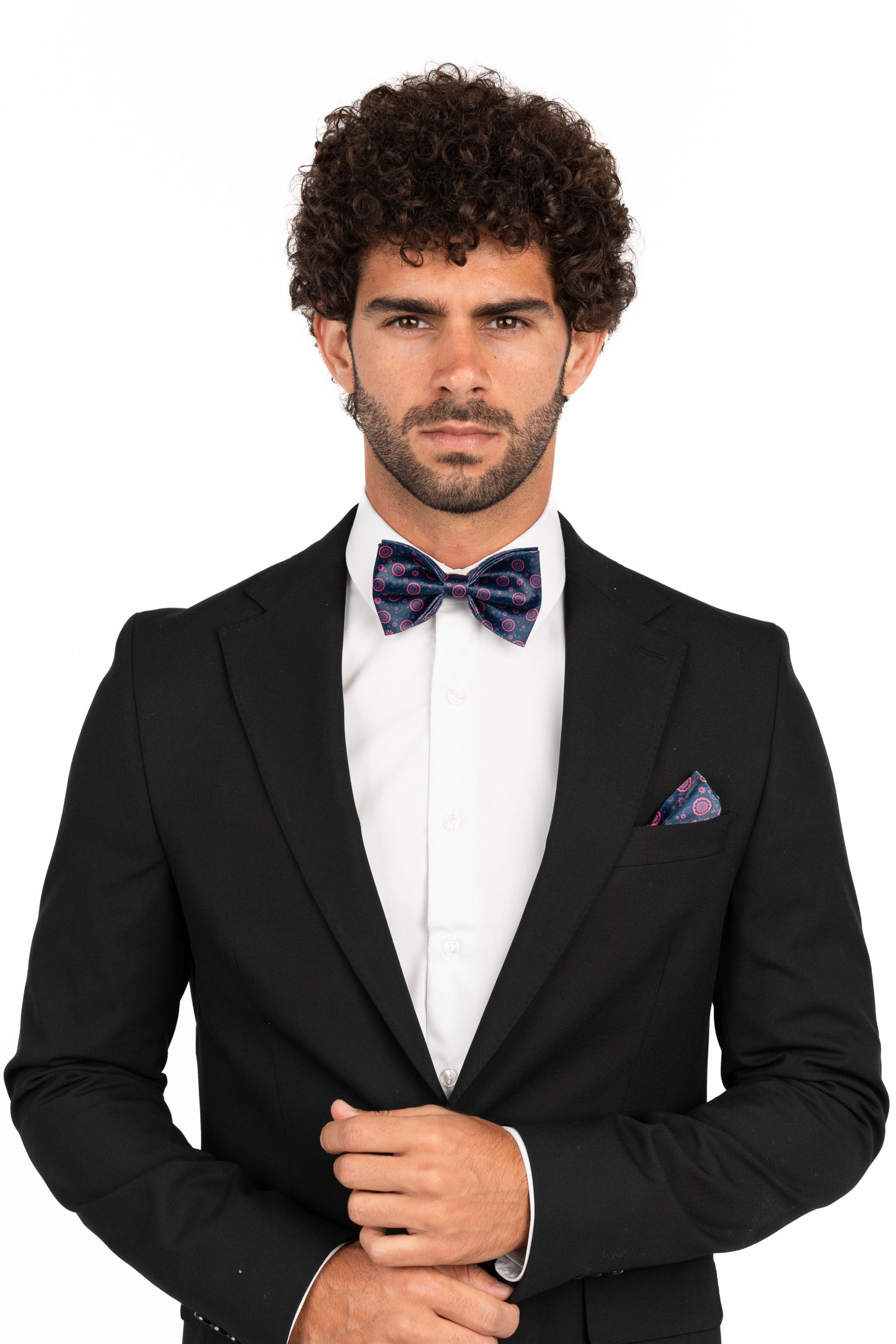 Man wearing a black tuxedo with a purple bow tie and pocket square on a white background