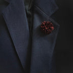 Dark blue blazer with a pine cone-shaped pin on a black background