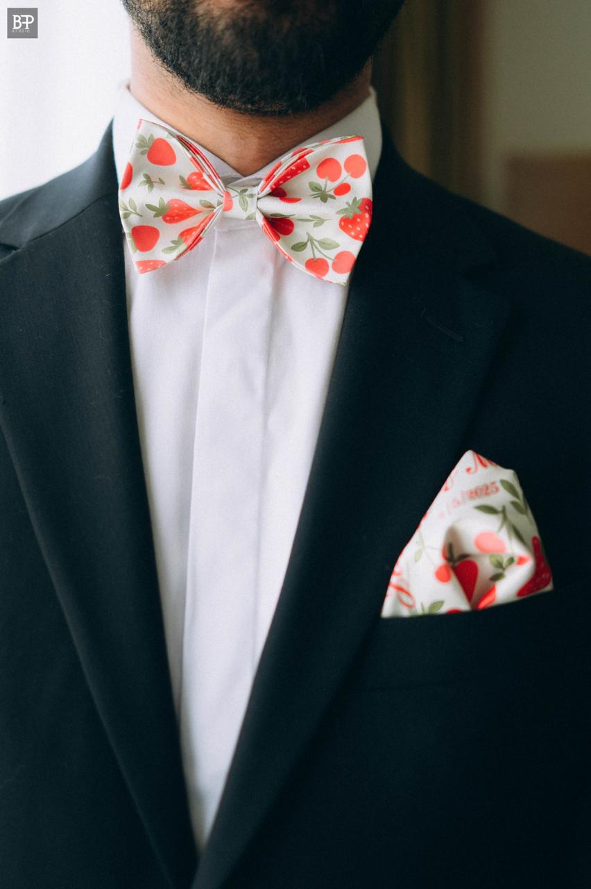 Man wearing a black suit with a floral bow tie and pocket square.