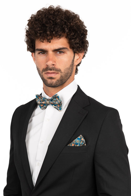 Man wearing a black suit with a white shirt and bow tie on a white background