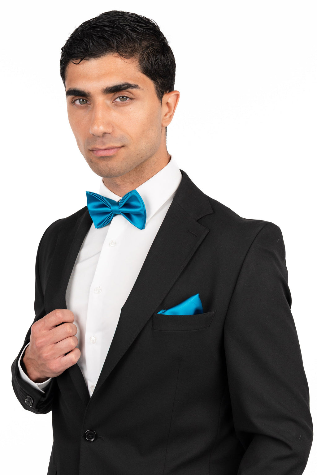 Man wearing a black suit with a blue bow tie and pocket square on a white background