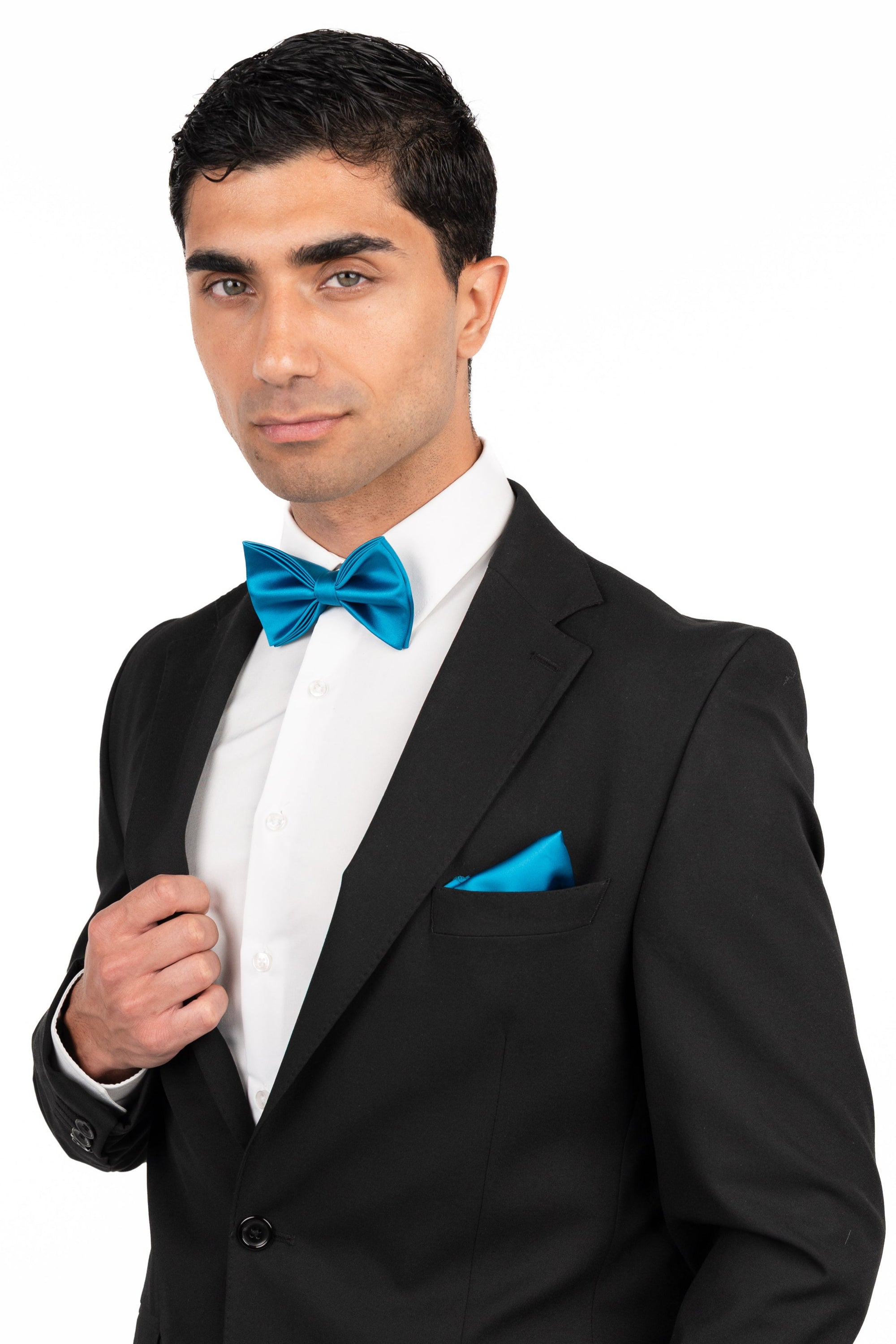 Man wearing a black suit with a blue bow tie and pocket square on a white background