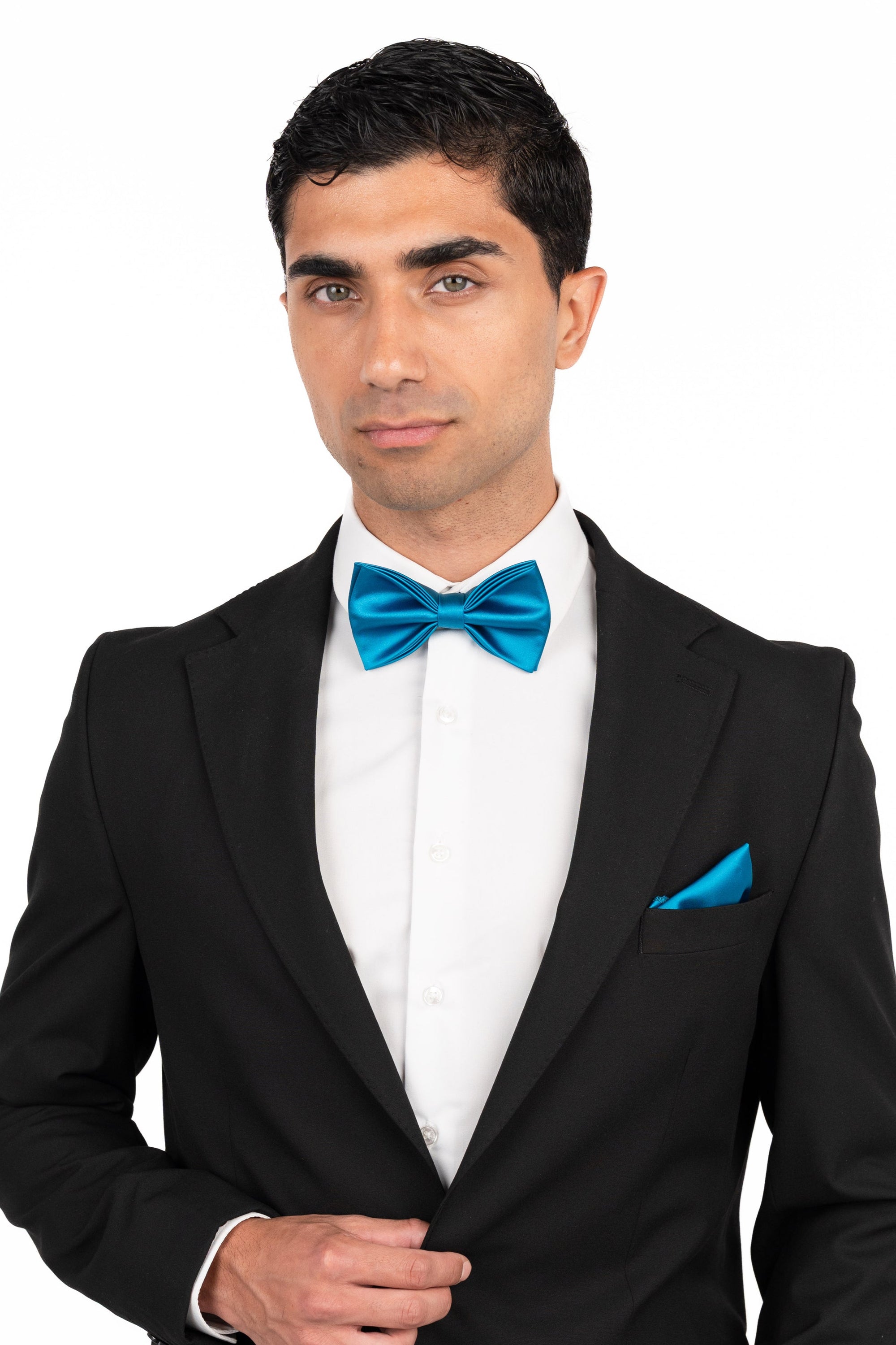 Man wearing a black suit with a blue bow tie on a white background