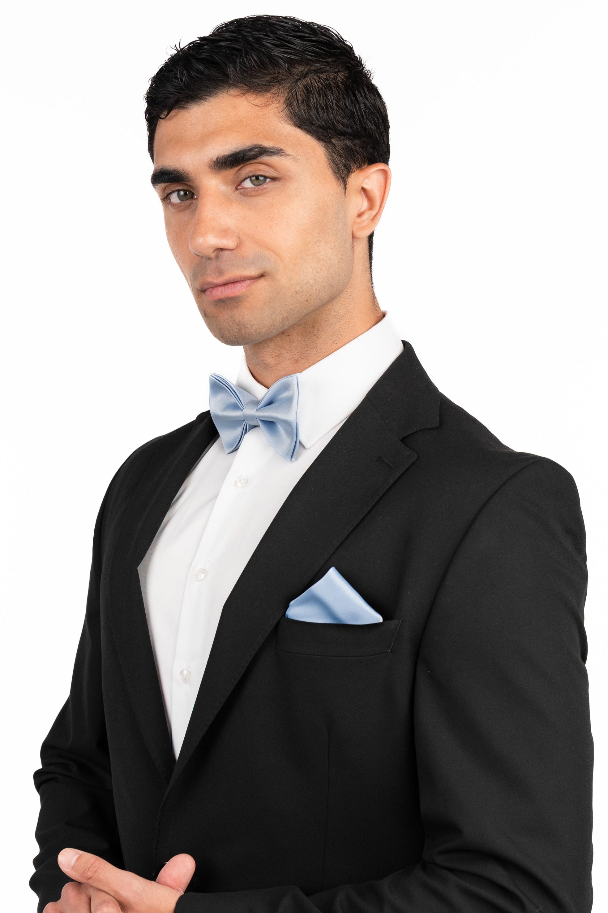 Man wearing a black tuxedo with a white shirt and light blue bow tie on a white background