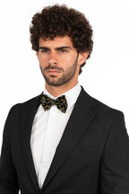 Man wearing a black tuxedo with a white shirt and bow tie on a white background