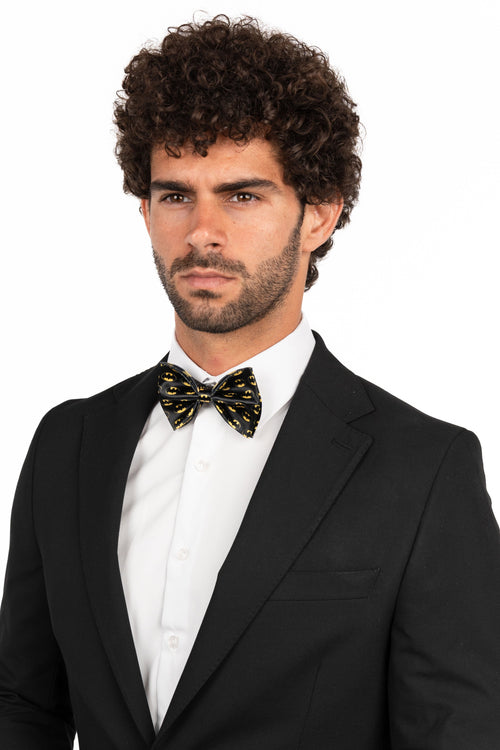Man wearing a black tuxedo with a white shirt and bow tie on a white background