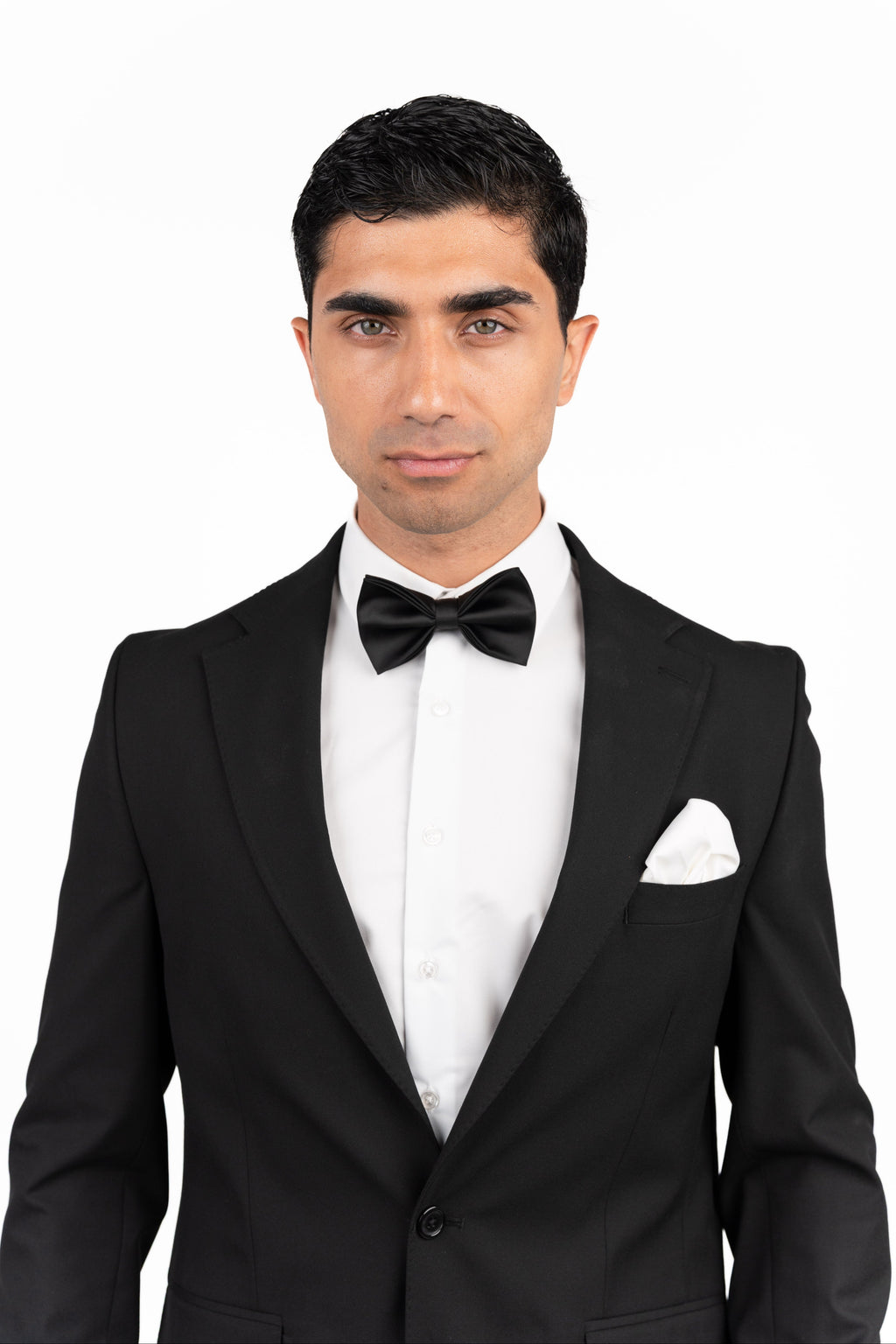Man wearing a black tuxedo with a bow tie on a white background
