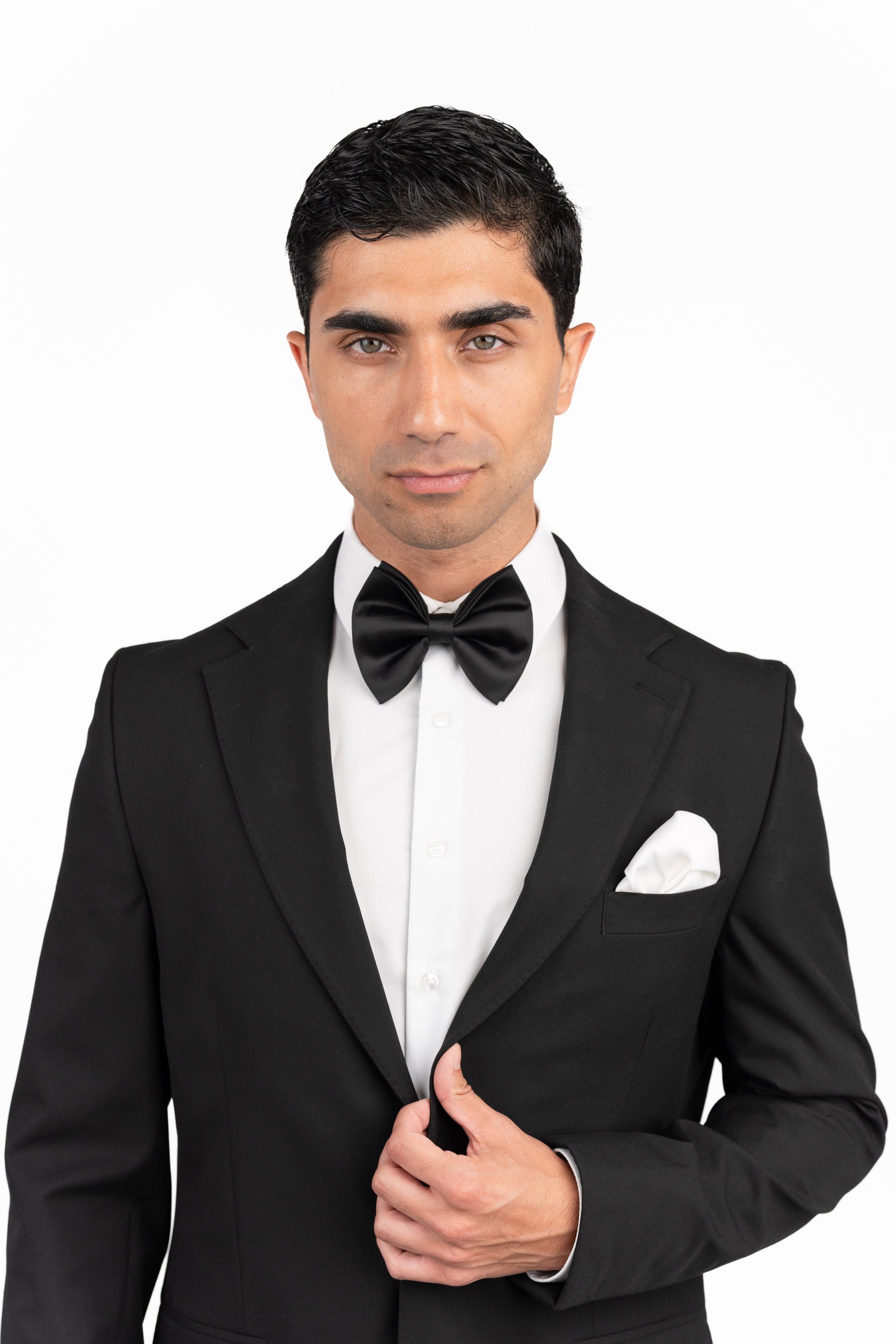 Man wearing a black tuxedo with a bow tie on a white background