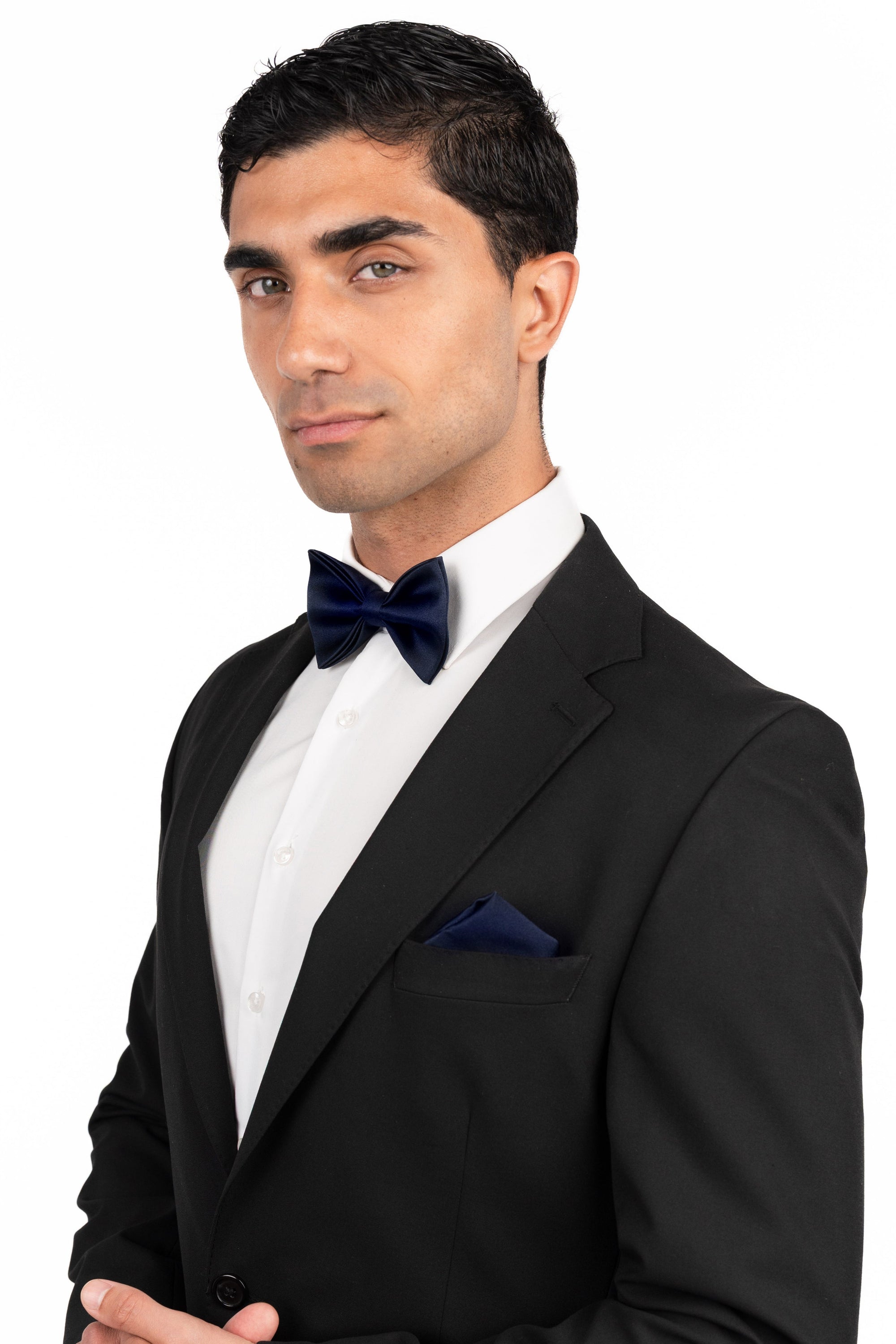 Man wearing a black tuxedo with a bow tie on a white background