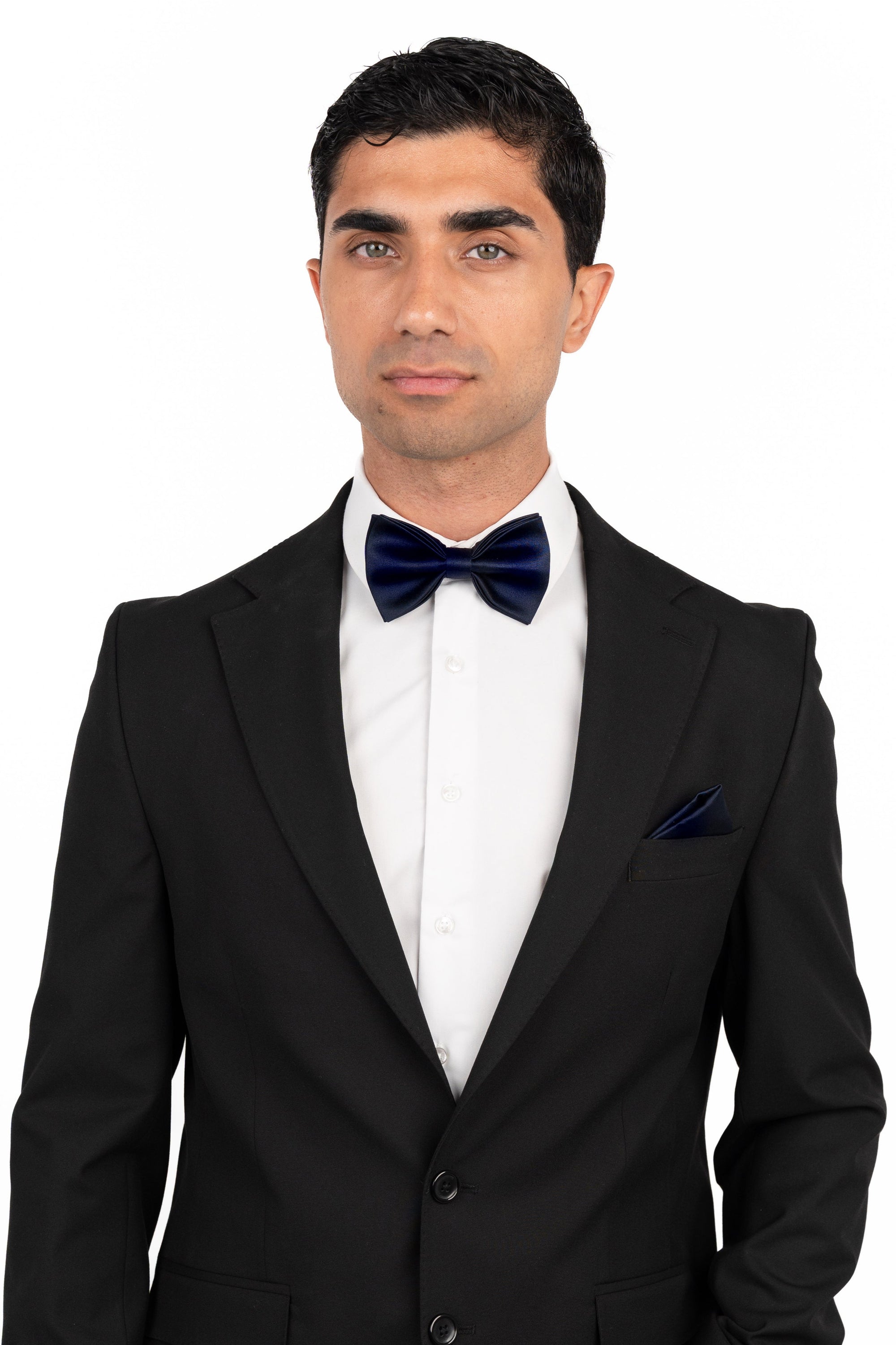 Man wearing a black suit with a white shirt and navy bow tie on a white background