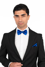 Man wearing a black tuxedo with a blue bow tie and pocket square on a white background