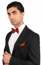 Man wearing a black tuxedo with a red bow tie and pocket square on a white background