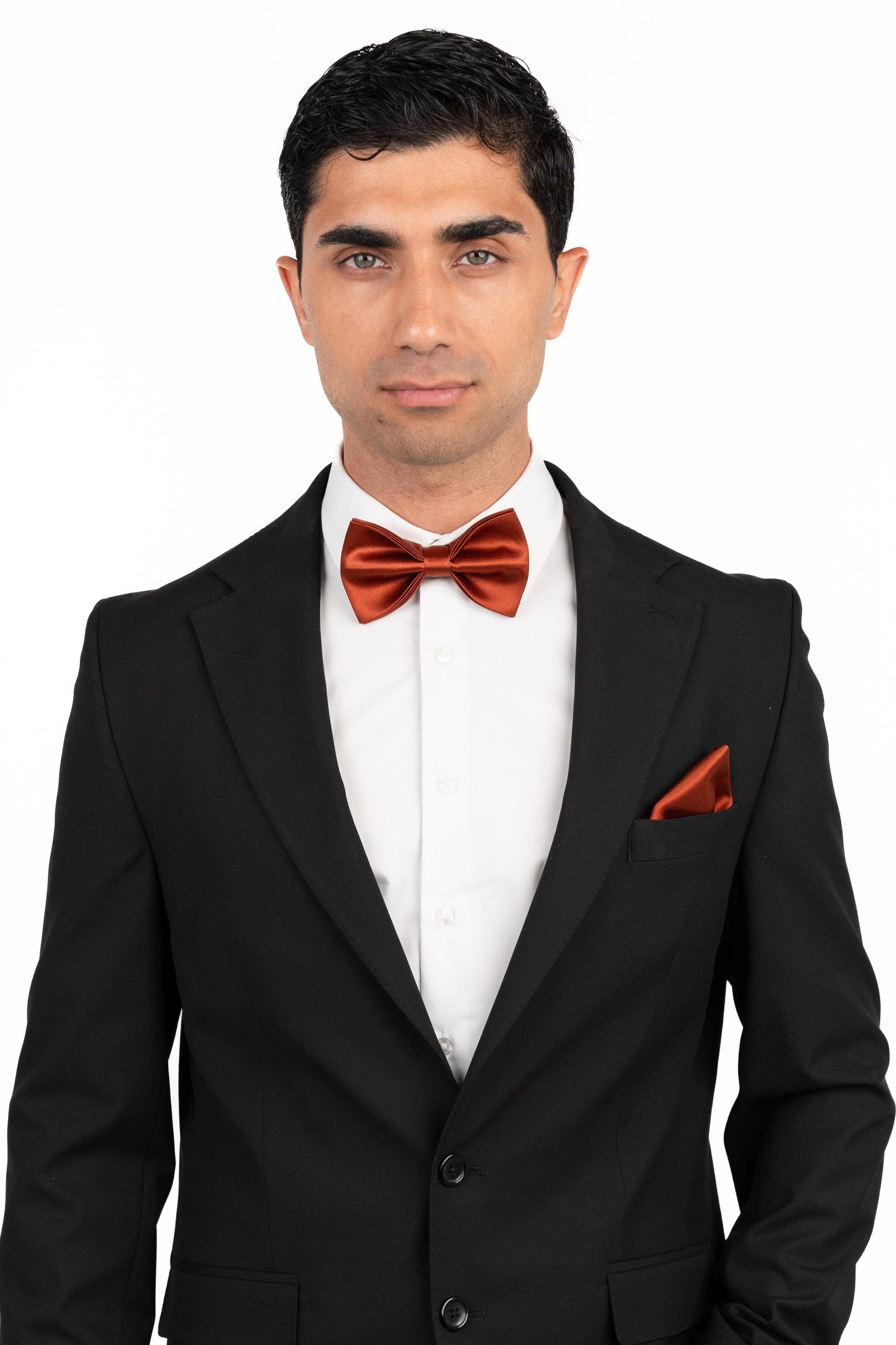 Man wearing a black suit with a red bow tie and pocket square on a white background