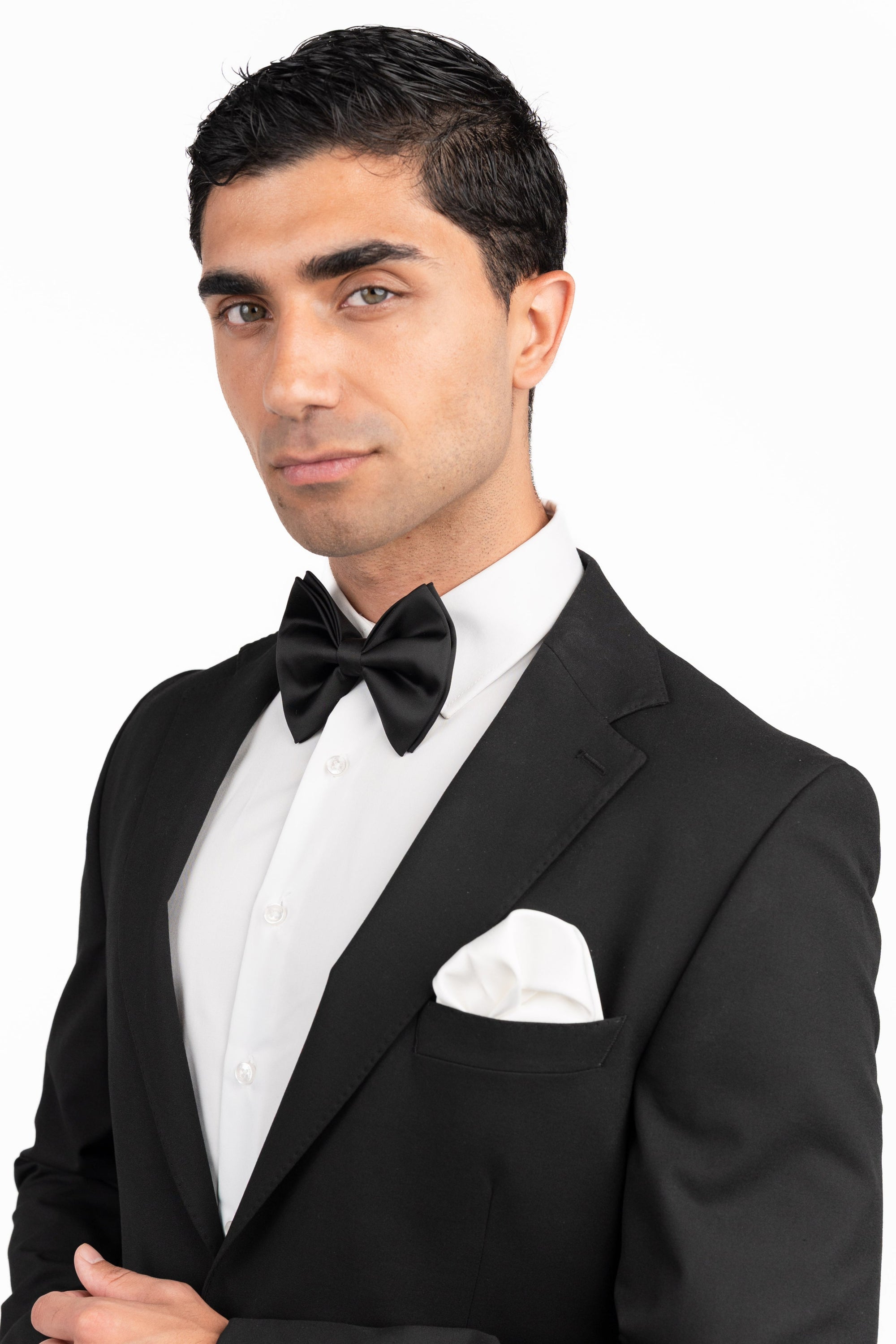 Man wearing a black tuxedo with a bow tie on a white background