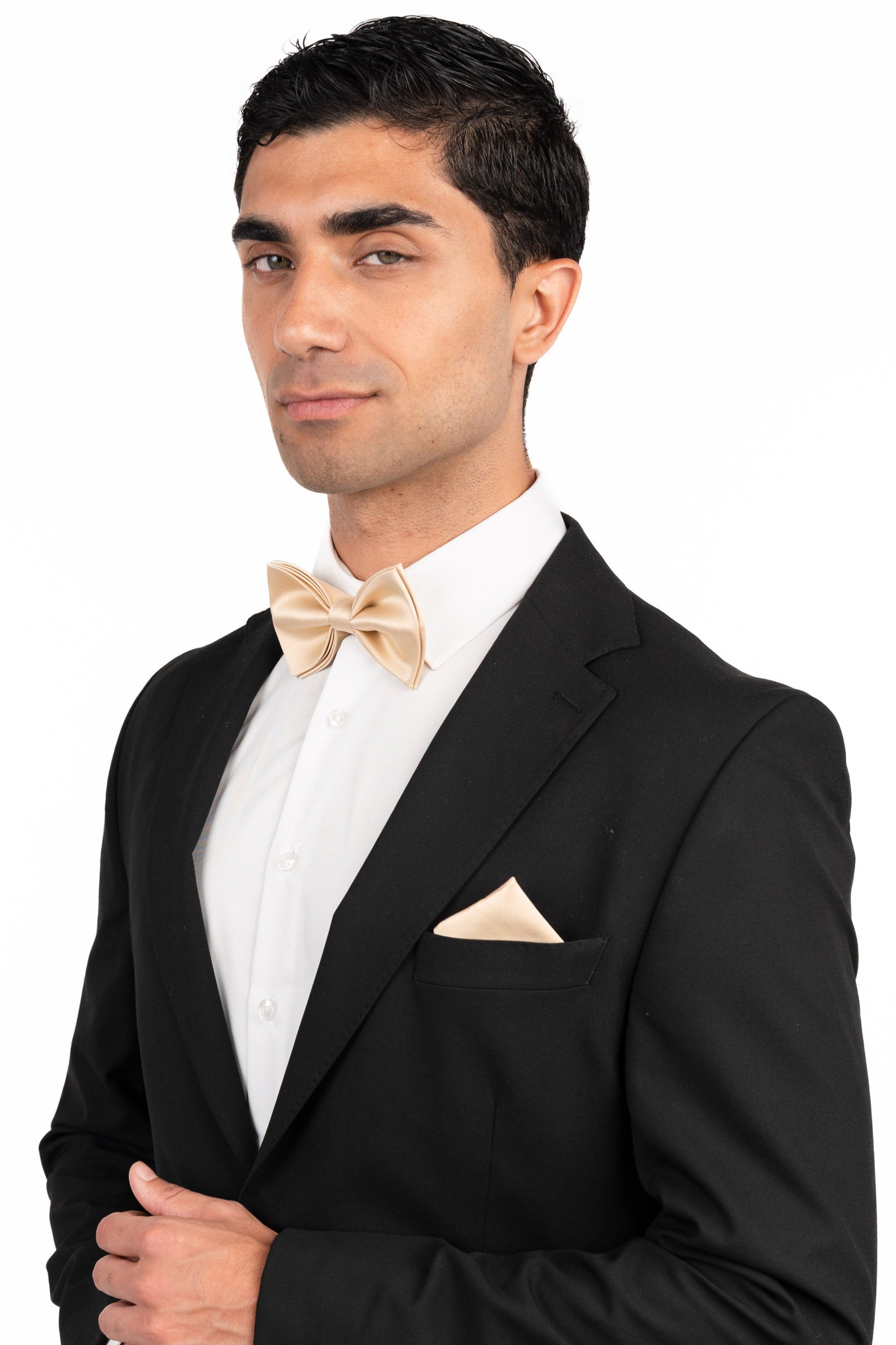 Man wearing a black tuxedo with a white shirt and bow tie on a white background