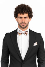 Man wearing a black suit with a white shirt and bow tie on a white background