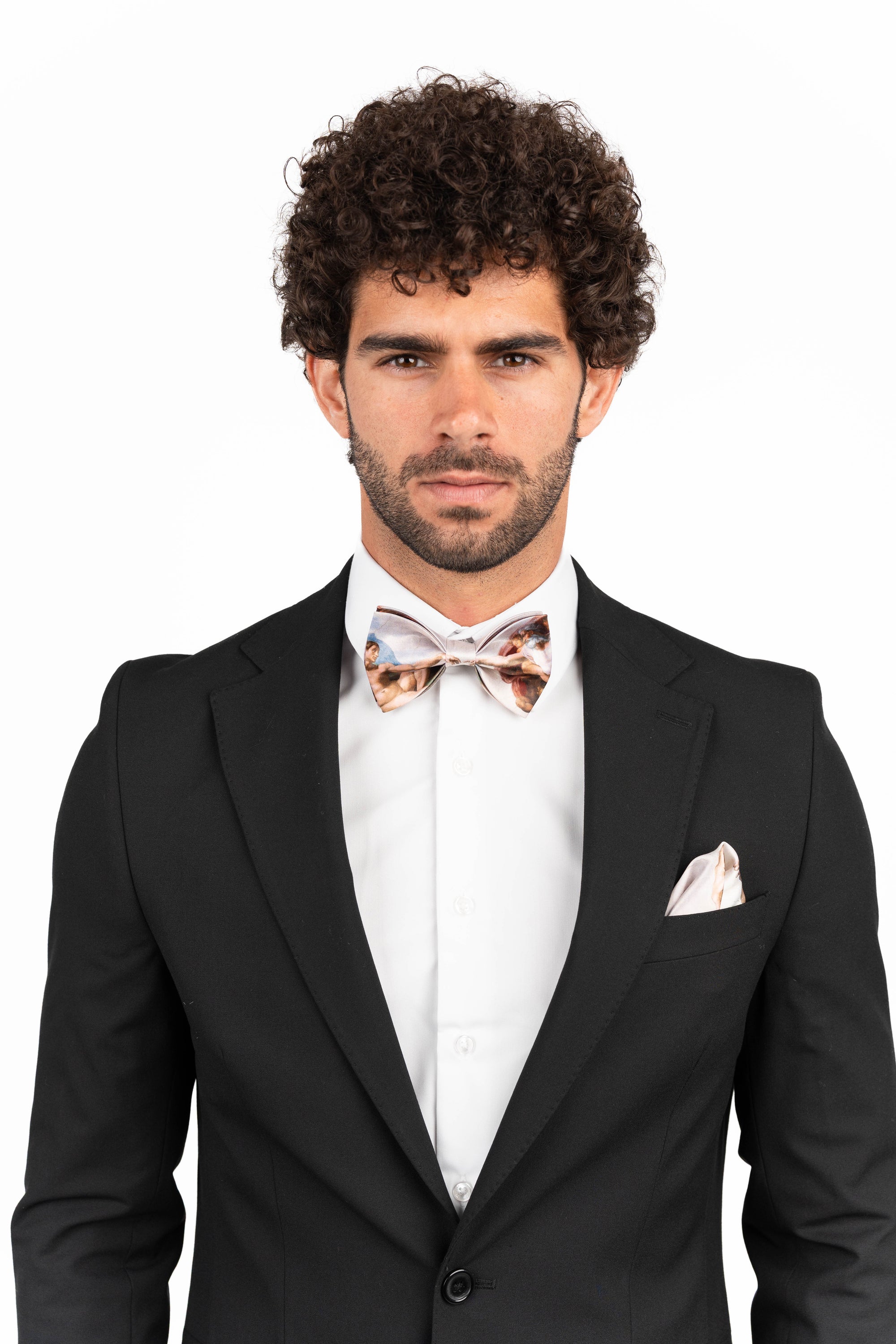 Man wearing a black suit with a white shirt and bow tie on a white background
