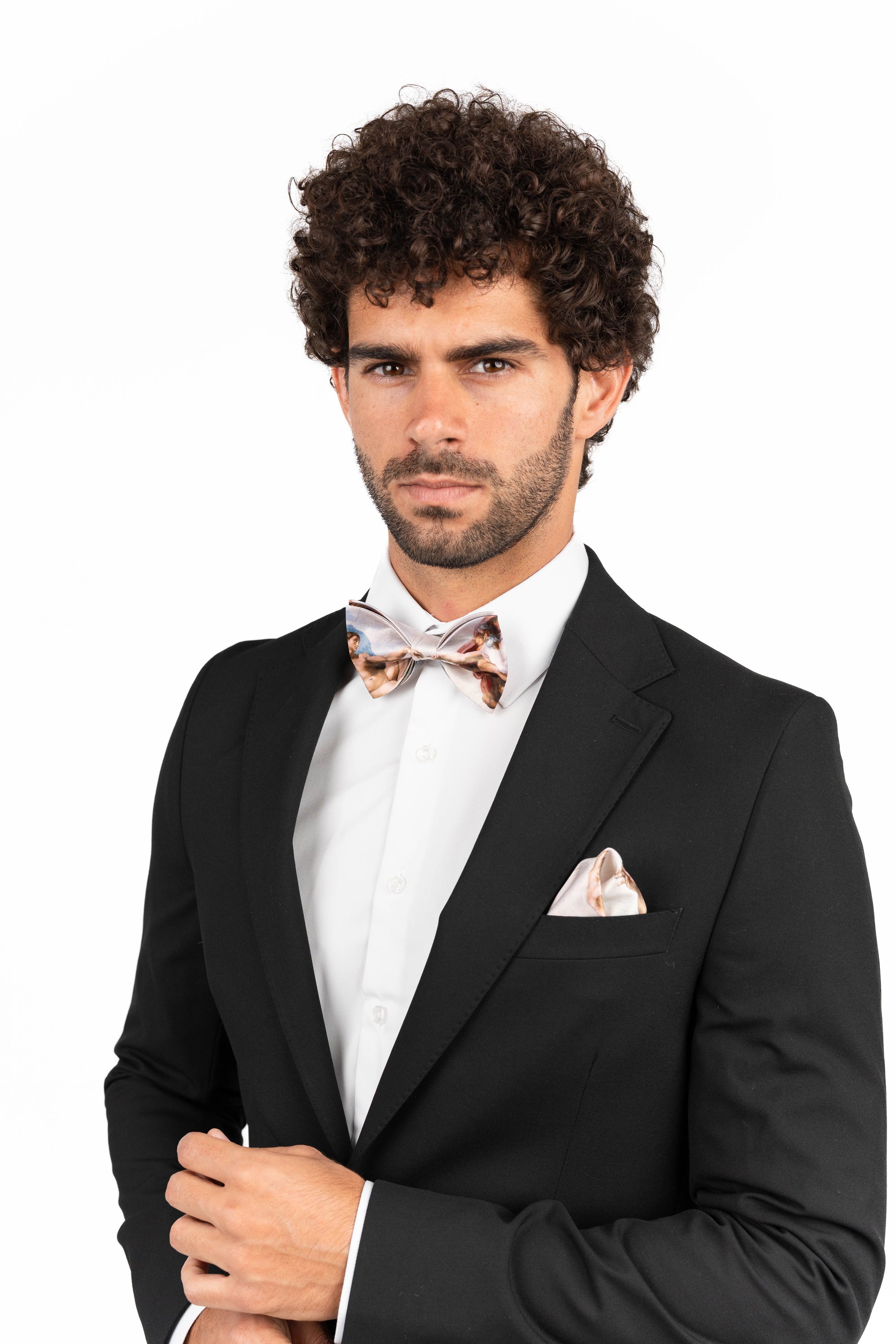Man wearing a black suit with a bow tie and pocket square on a white background