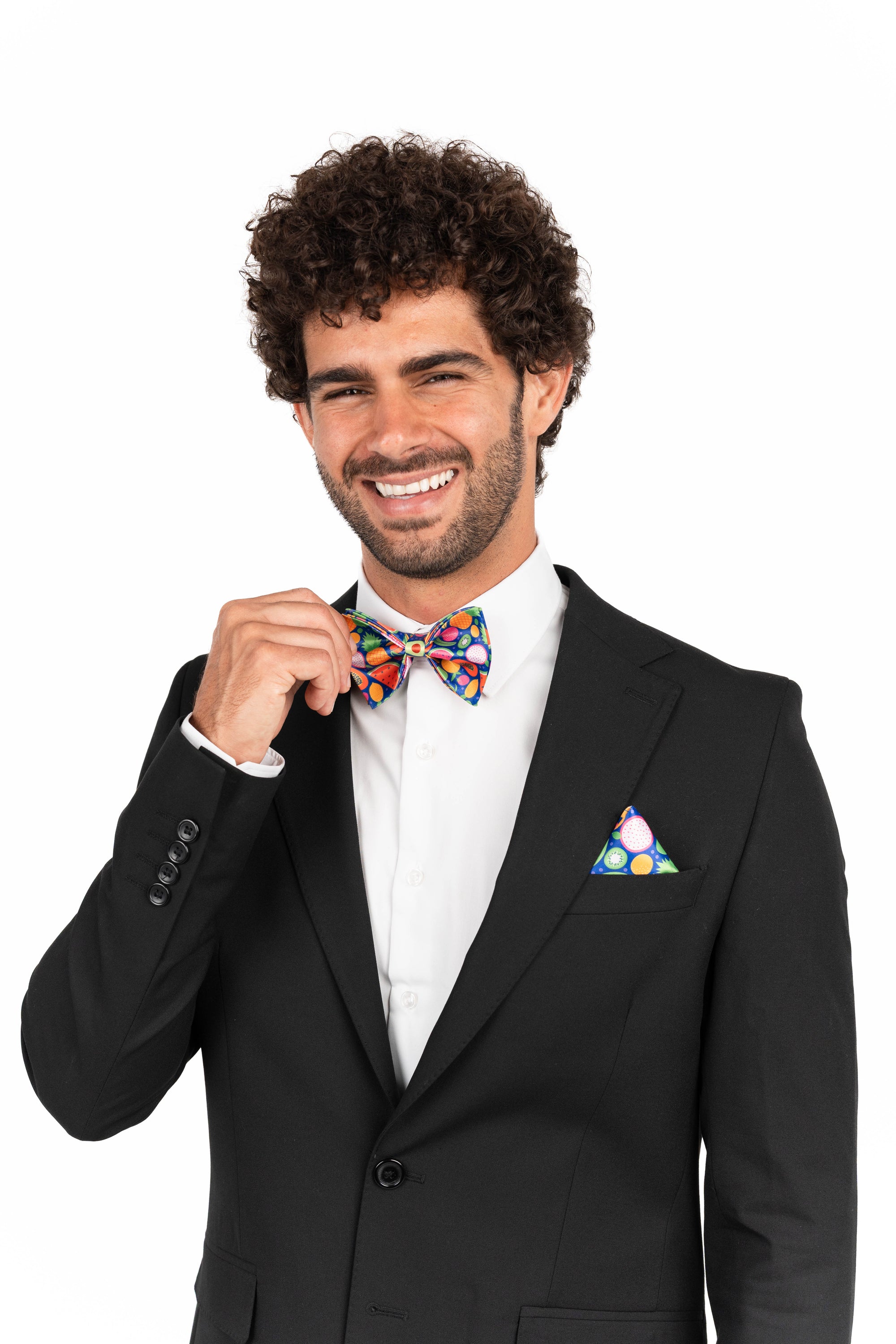 Man wearing a black suit with a colorful bow tie and pocket square on a white background