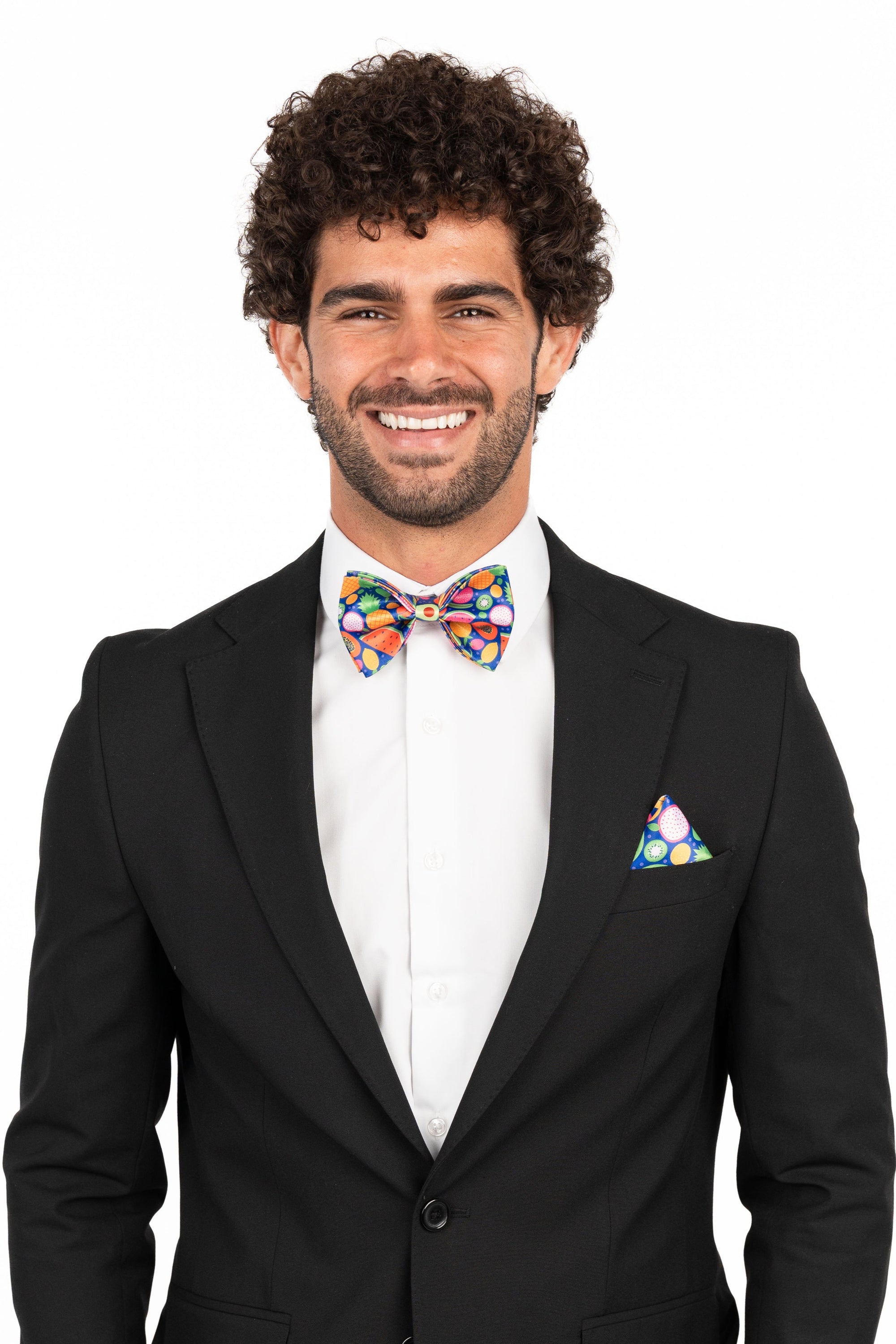Man wearing a black suit with a colorful bow tie and pocket square on a white background