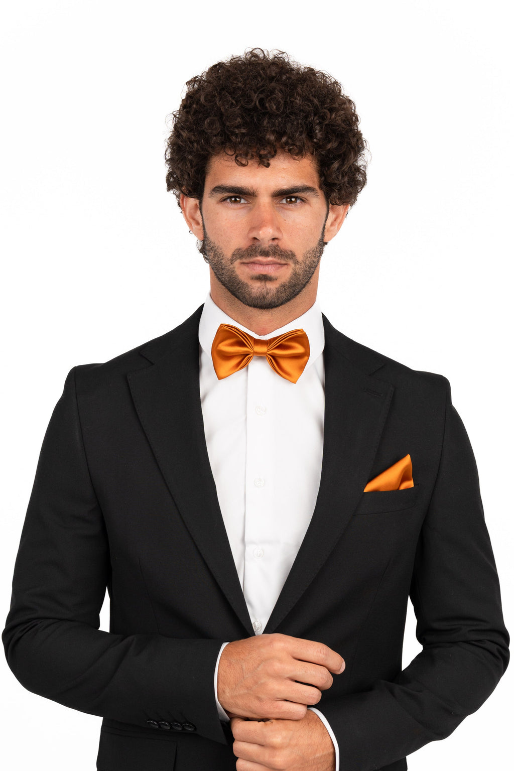 Man wearing a black suit with an orange bow tie and pocket square on a white background