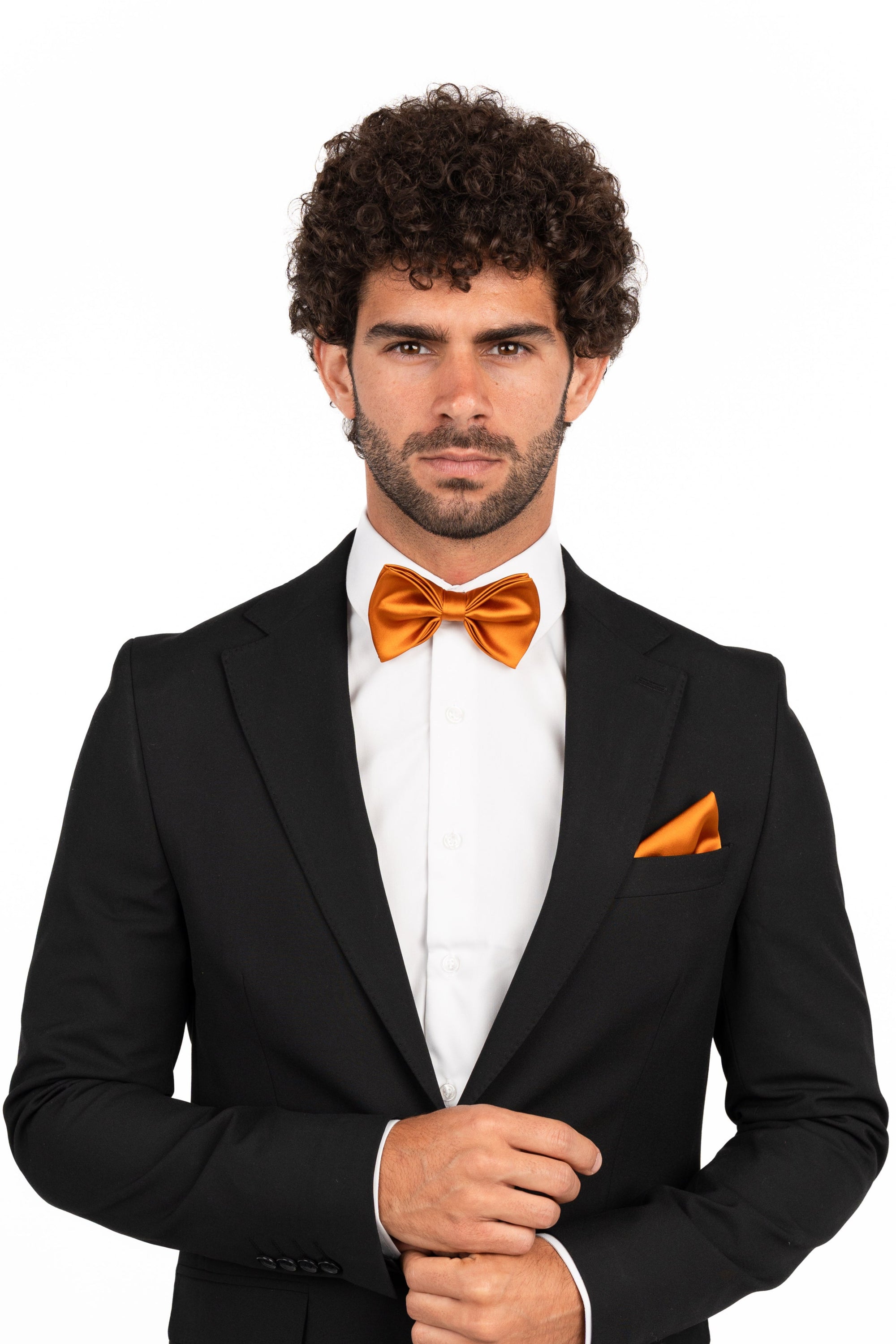 Man wearing a black suit with an orange bow tie and pocket square on a white background