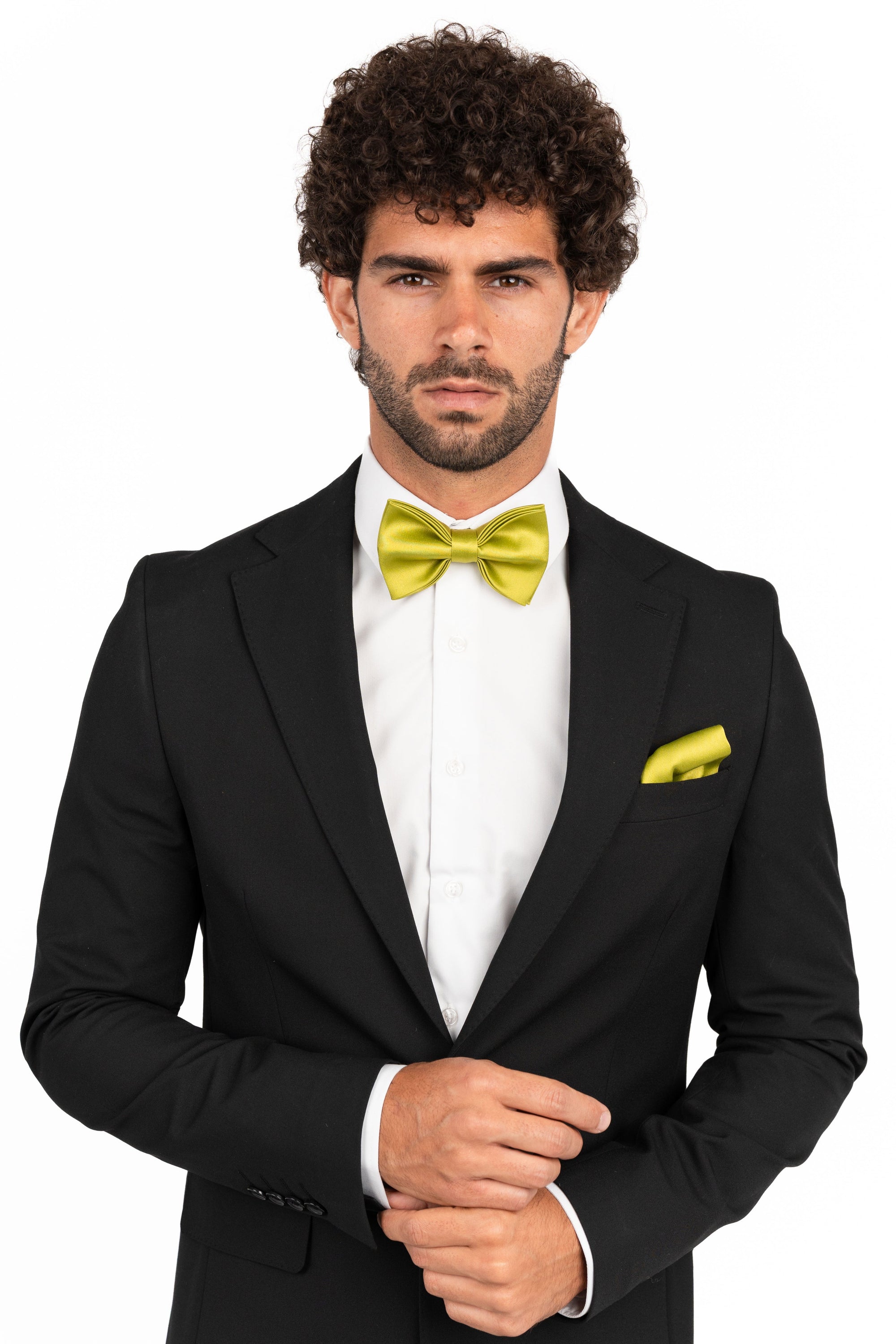 Man wearing a black tuxedo with a yellow bow tie and pocket square on a white background