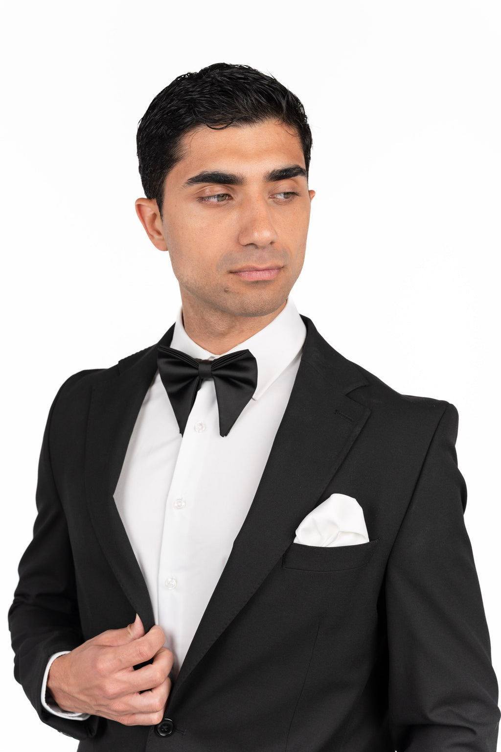 Man wearing a black tuxedo with a white shirt and bow tie on a white background