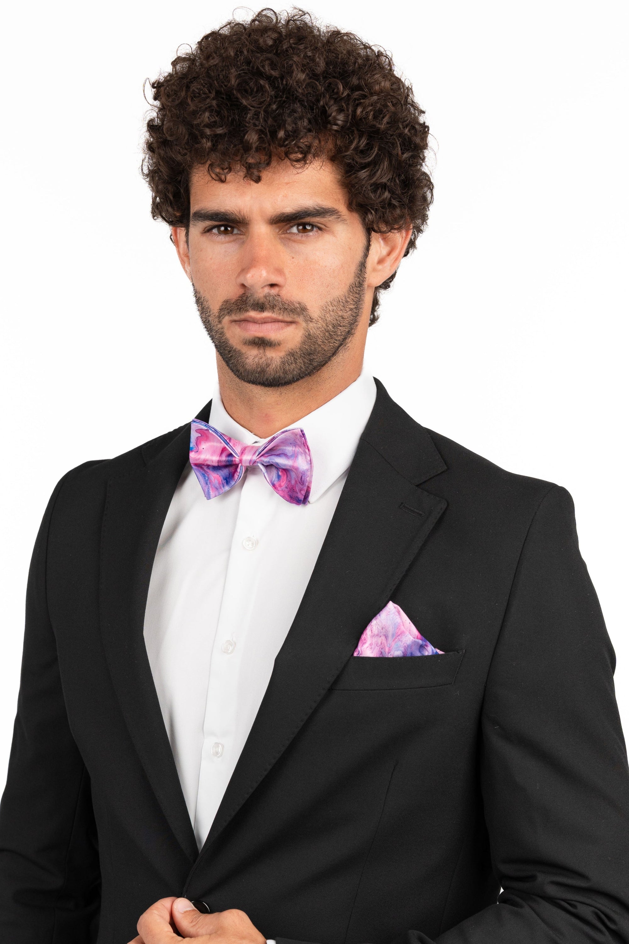 Man wearing a black suit with a colorful bow tie and pocket square on a white background