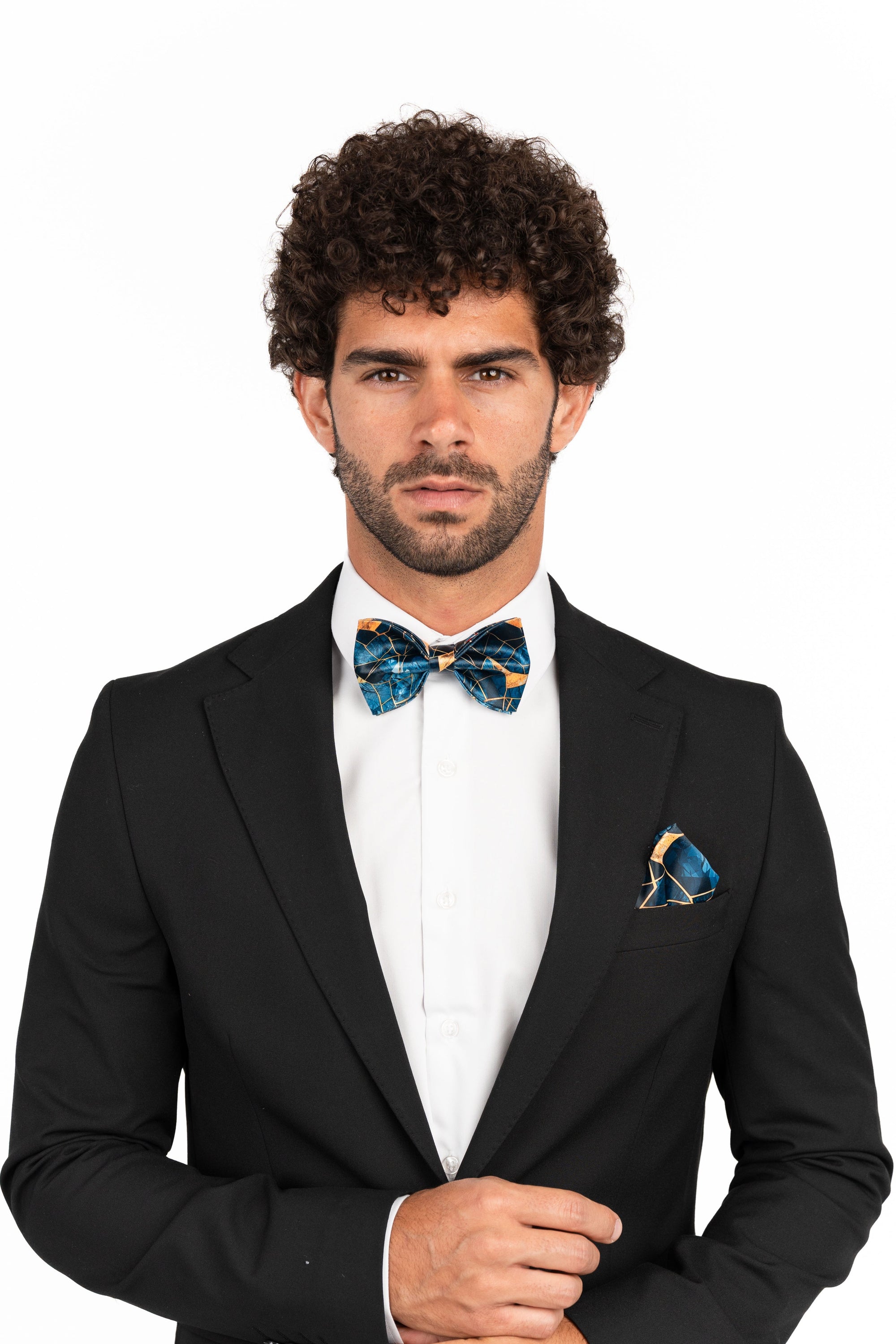 Man wearing a black suit with a colorful bow tie and pocket square on a white background
