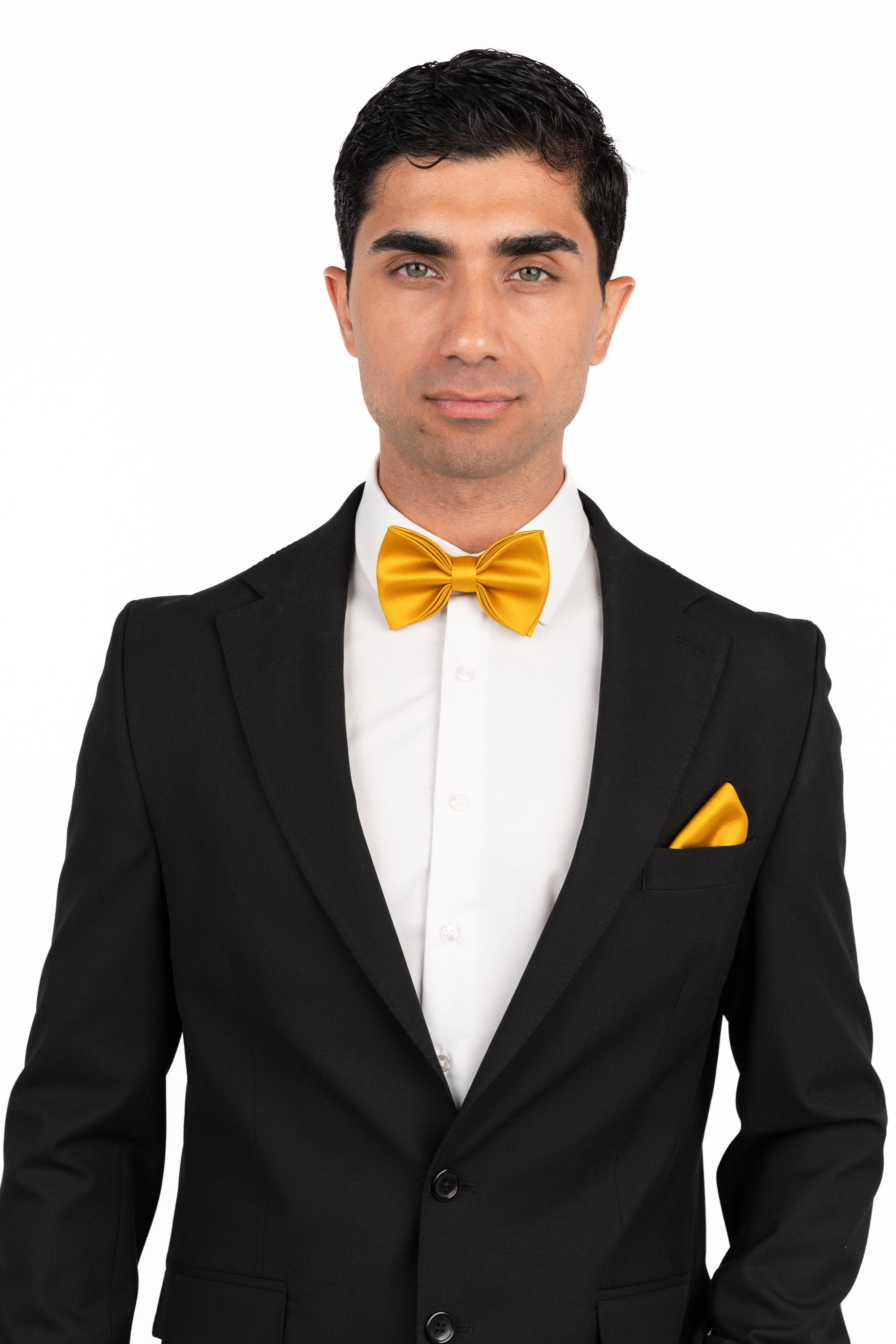 Man wearing a black tuxedo with a yellow bow tie and pocket square on a white background