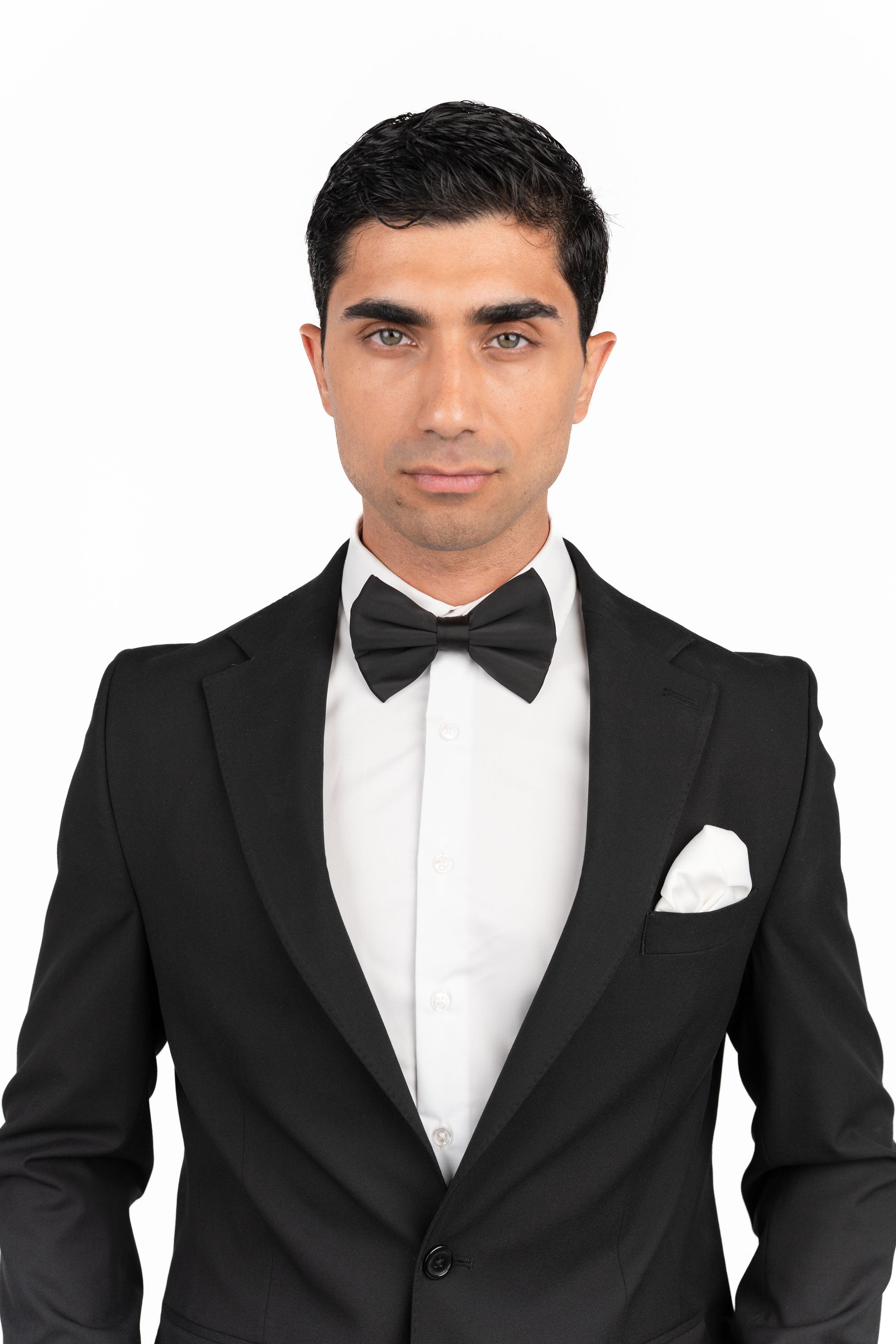 Man wearing a black tuxedo with a bow tie on a white background