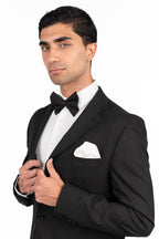 Man wearing a black tuxedo with a white shirt and bow tie on a white background