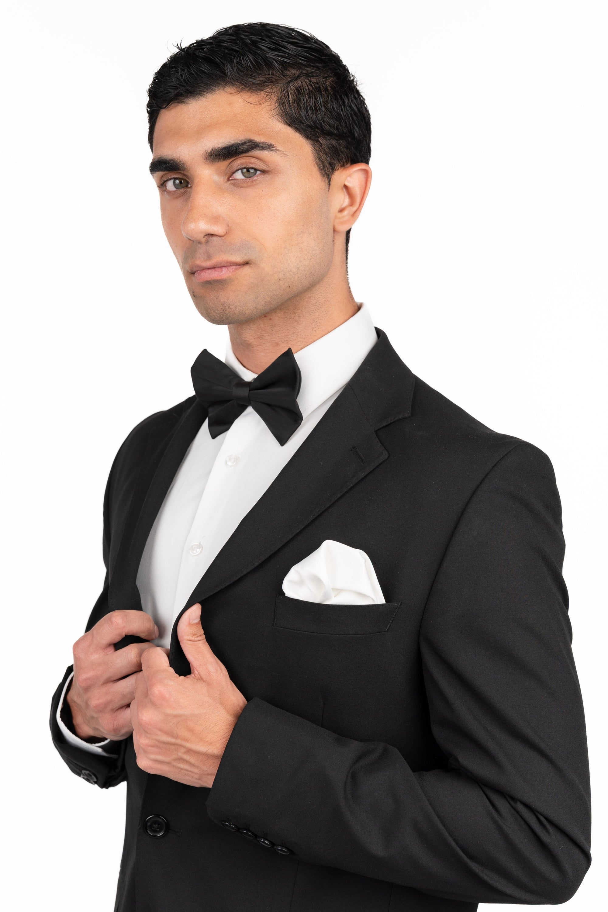 Man wearing a black tuxedo with a white shirt and bow tie on a white background