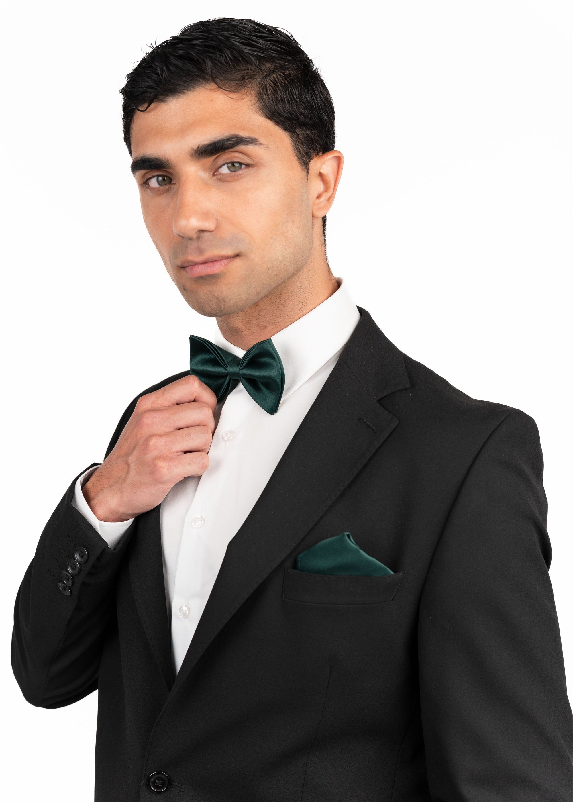 Man adjusting his green bow tie in a black suit on a white background