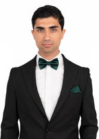 Man wearing a black suit with green bow tie and pocket square on a white background