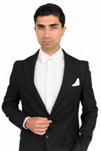 Man wearing a black tuxedo with a white shirt and bow tie on a white background