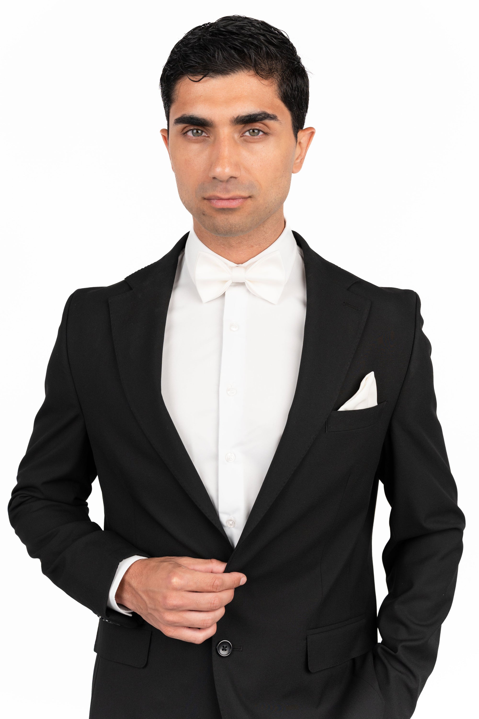Man wearing a black tuxedo with a white shirt and bow tie on a white background