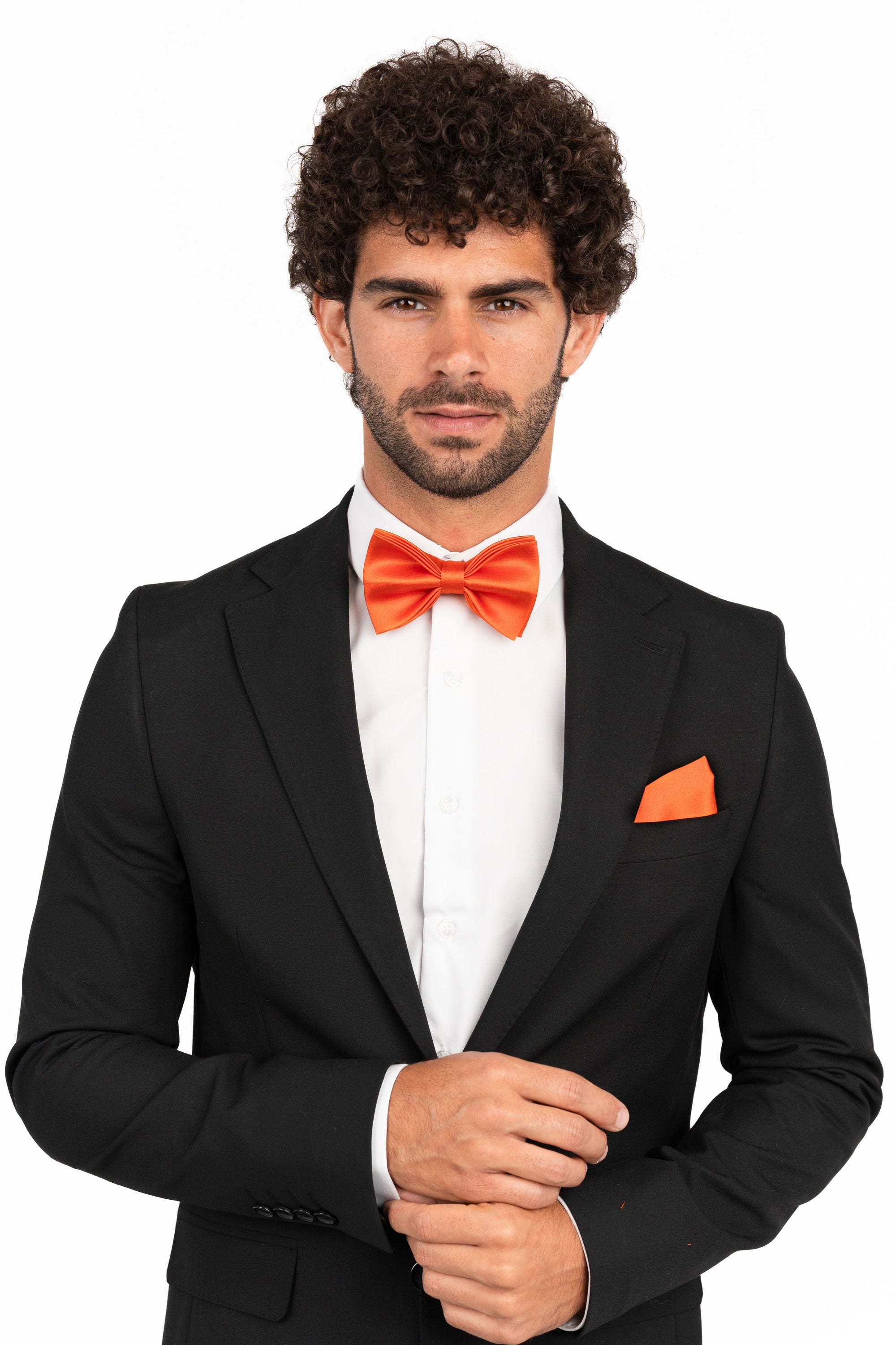 Man wearing a black suit with an orange bow tie and pocket square on a white background
