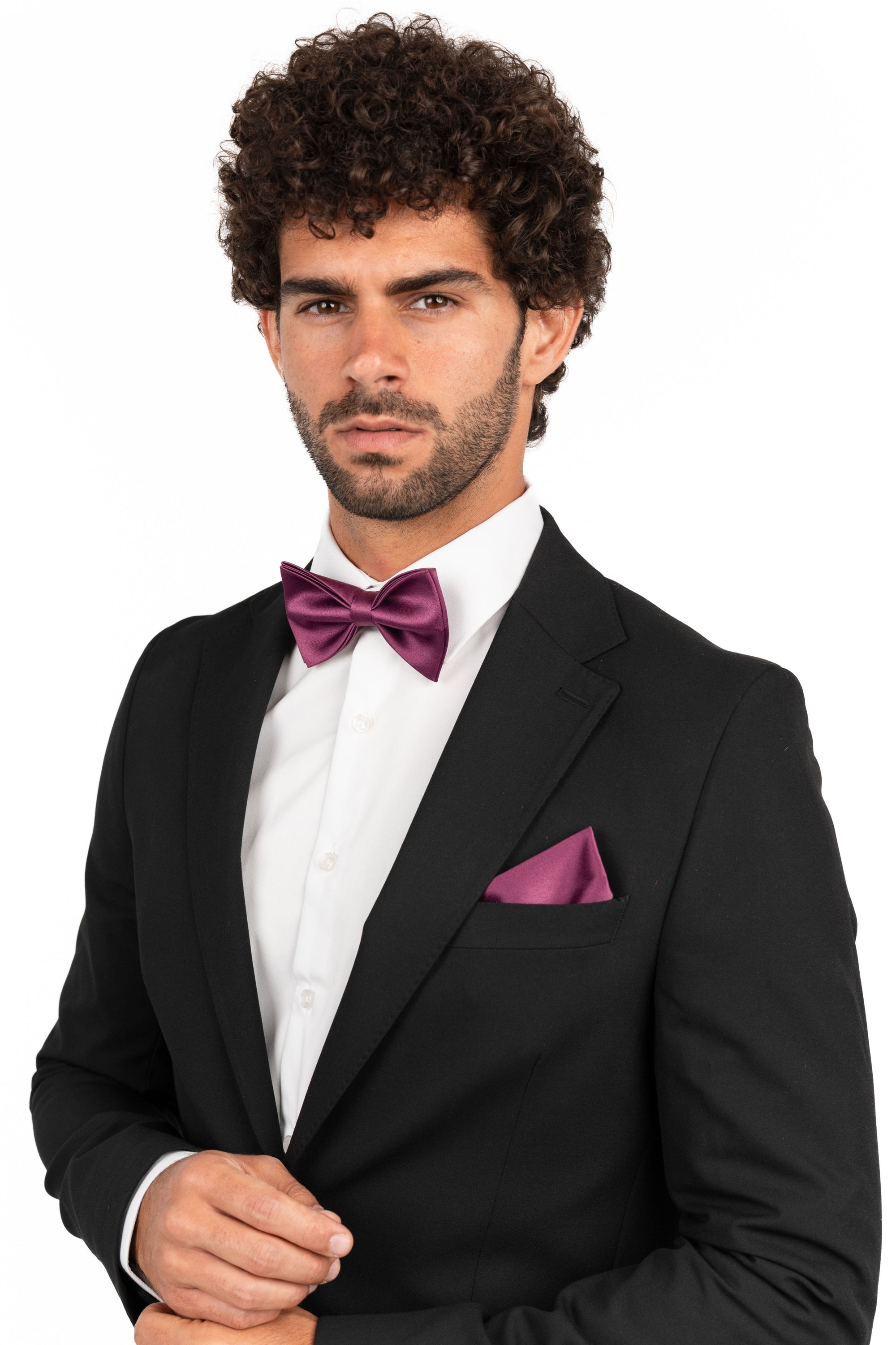 Man wearing a black tuxedo with a purple bow tie and pocket square on a white background