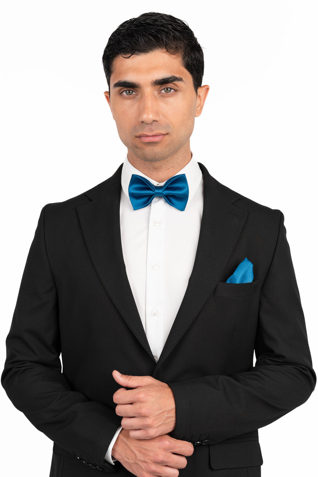 Man wearing a black tuxedo with a blue bow tie and pocket square on a white background