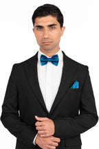 Man wearing a black tuxedo with a blue bow tie and pocket square on a white background
