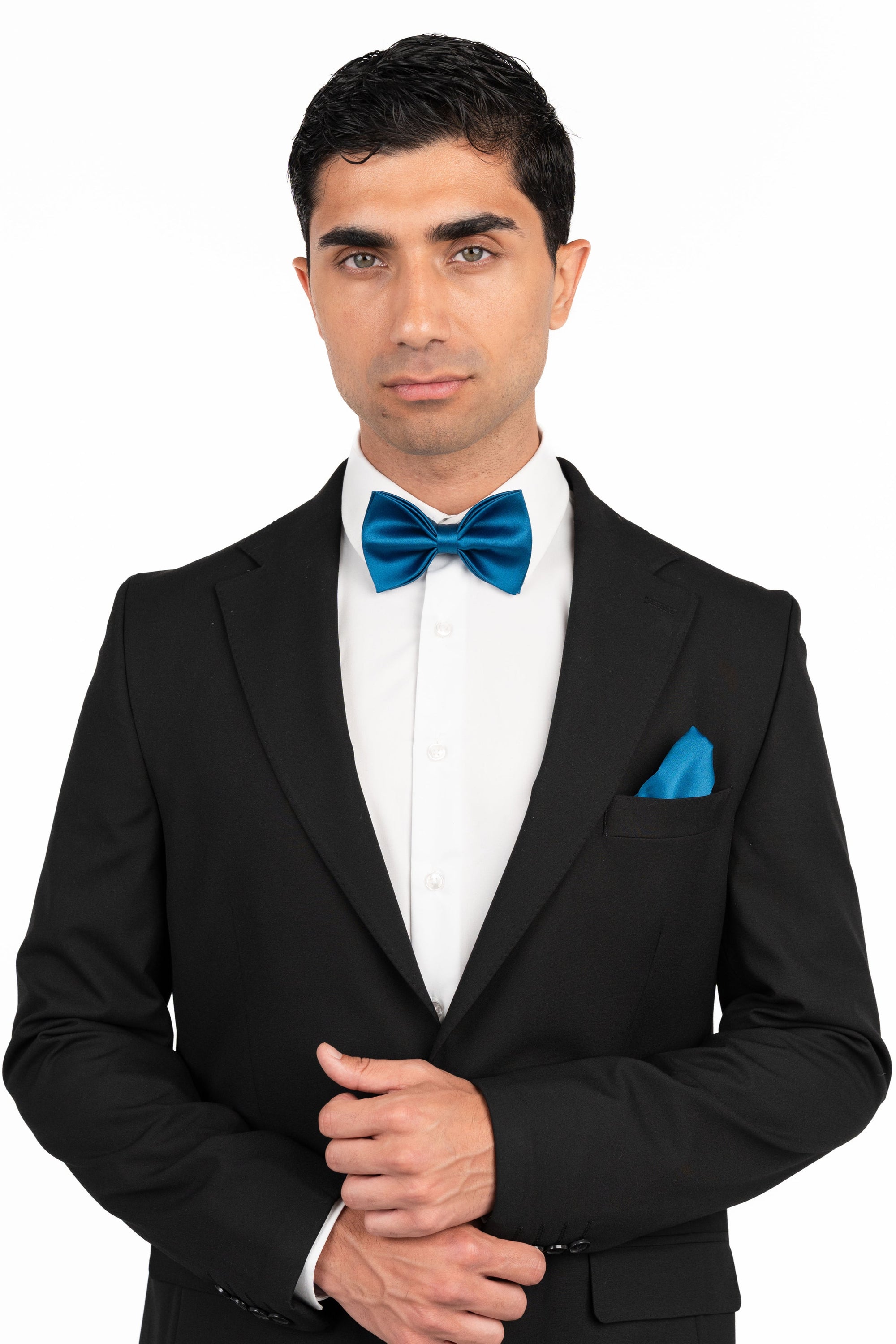 Man wearing a black tuxedo with a blue bow tie and pocket square on a white background