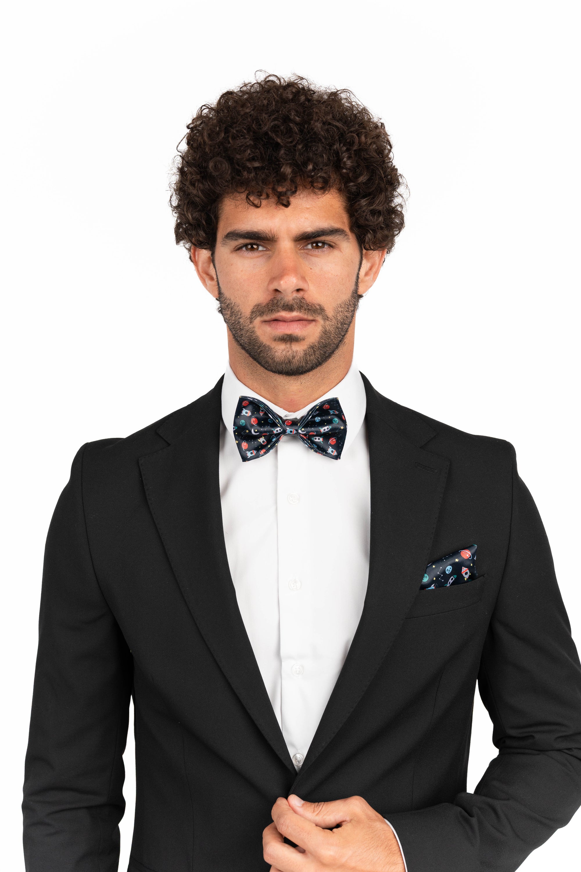 Man wearing a black suit with a  space bow tie and pocket square on a white background