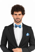 Man wearing a black suit with a blue bow tie and pocket square on a white background