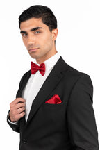 Man in a black tuxedo with a red bow tie and pocket square on a white background